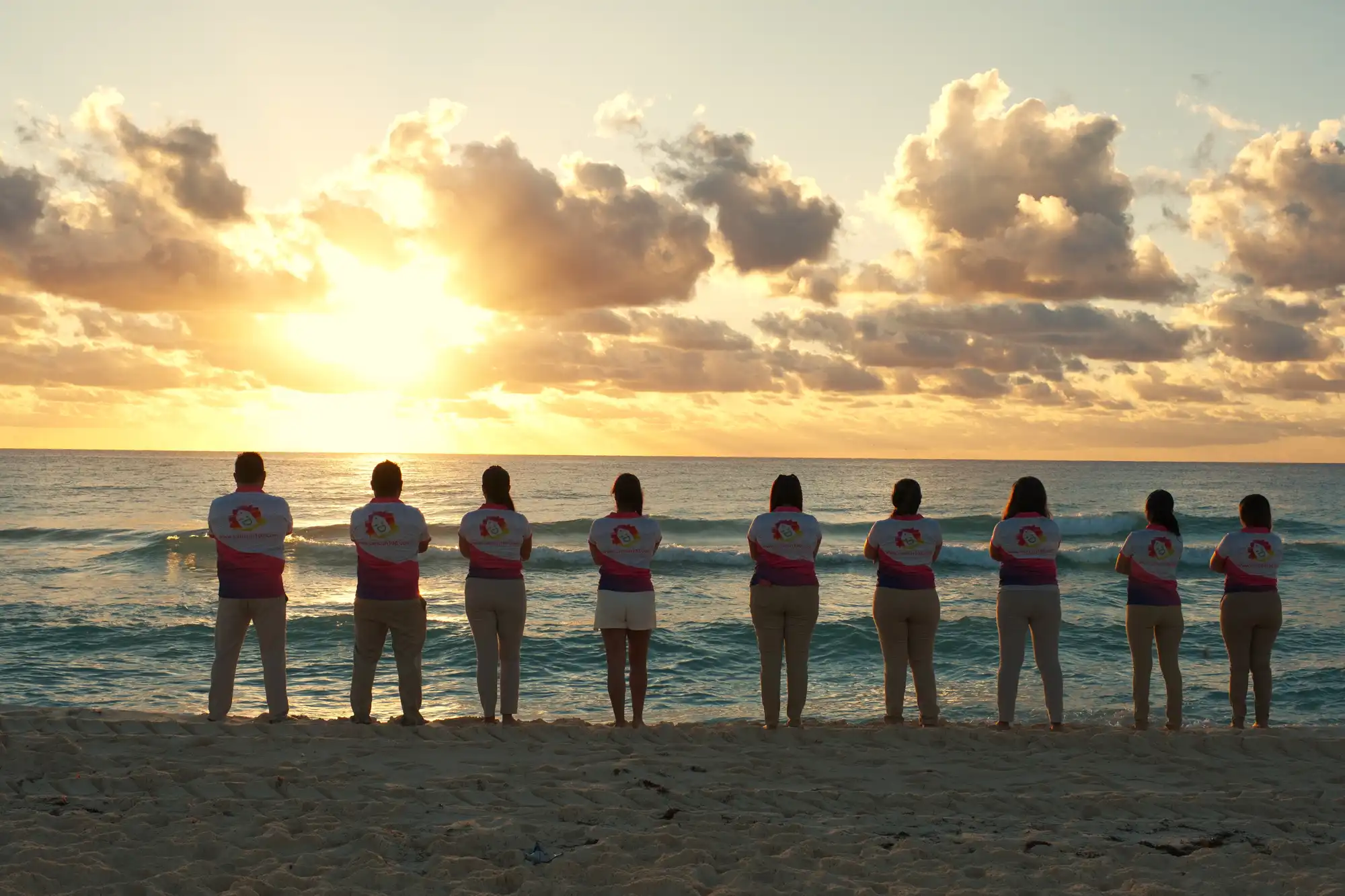 A equipe da Cancun100 em frente ao mar na praia de Cancún ao amanhecer