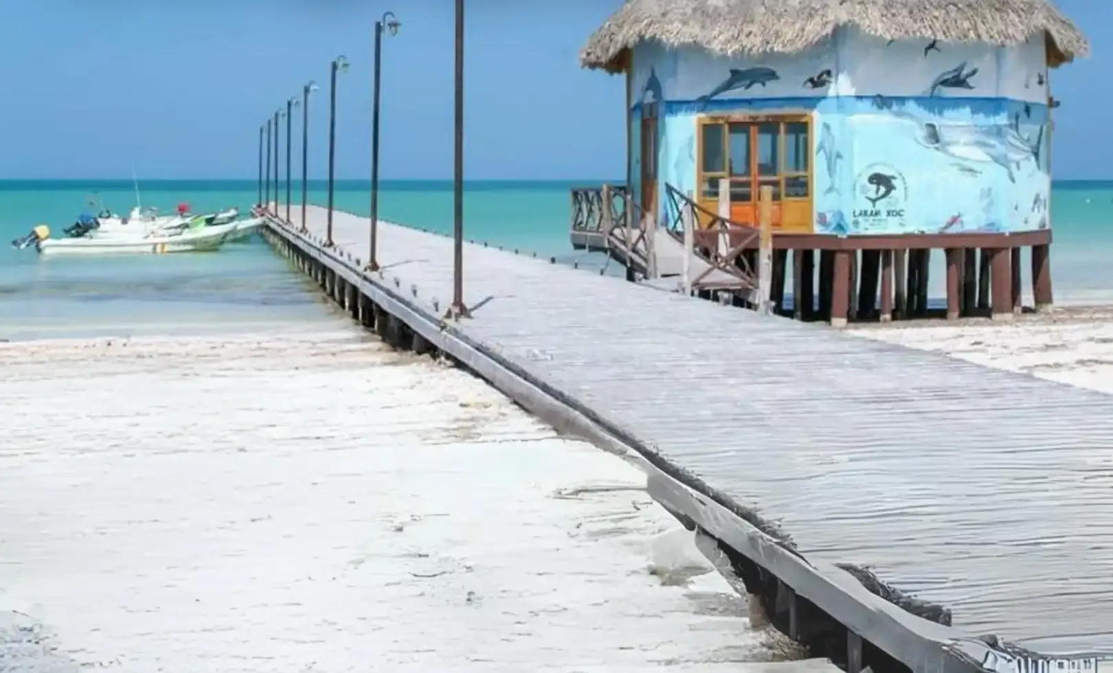 Muelle de madera y palapa sobre el agua turquesa en Holbox