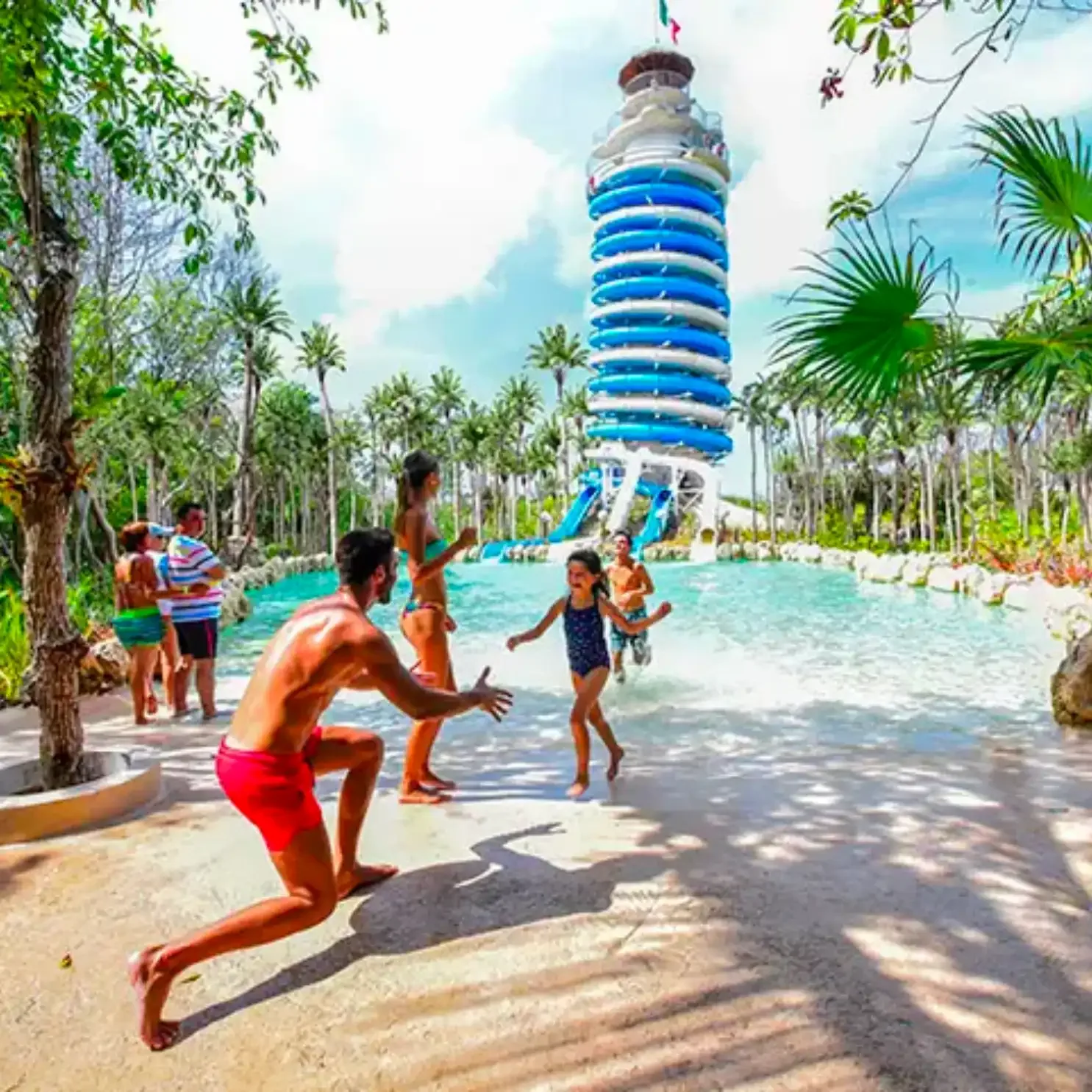 Familia jugando en el agua frente al faro mirador de Xel-Há